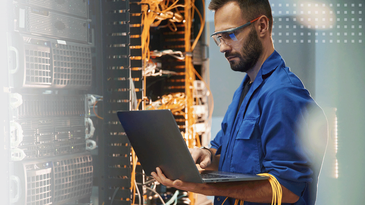 male engineer using laptop in computer server room